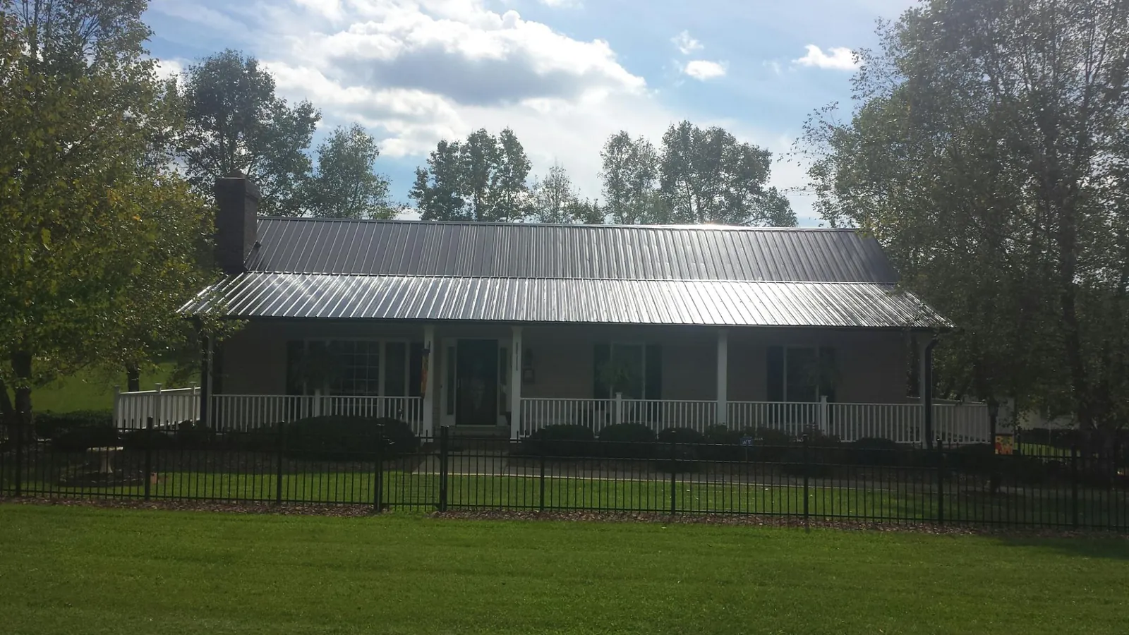 Gray metal roof on a brick ranch with a full width front porch — Gutter Guard Installation work by our crew in Lawrenceville